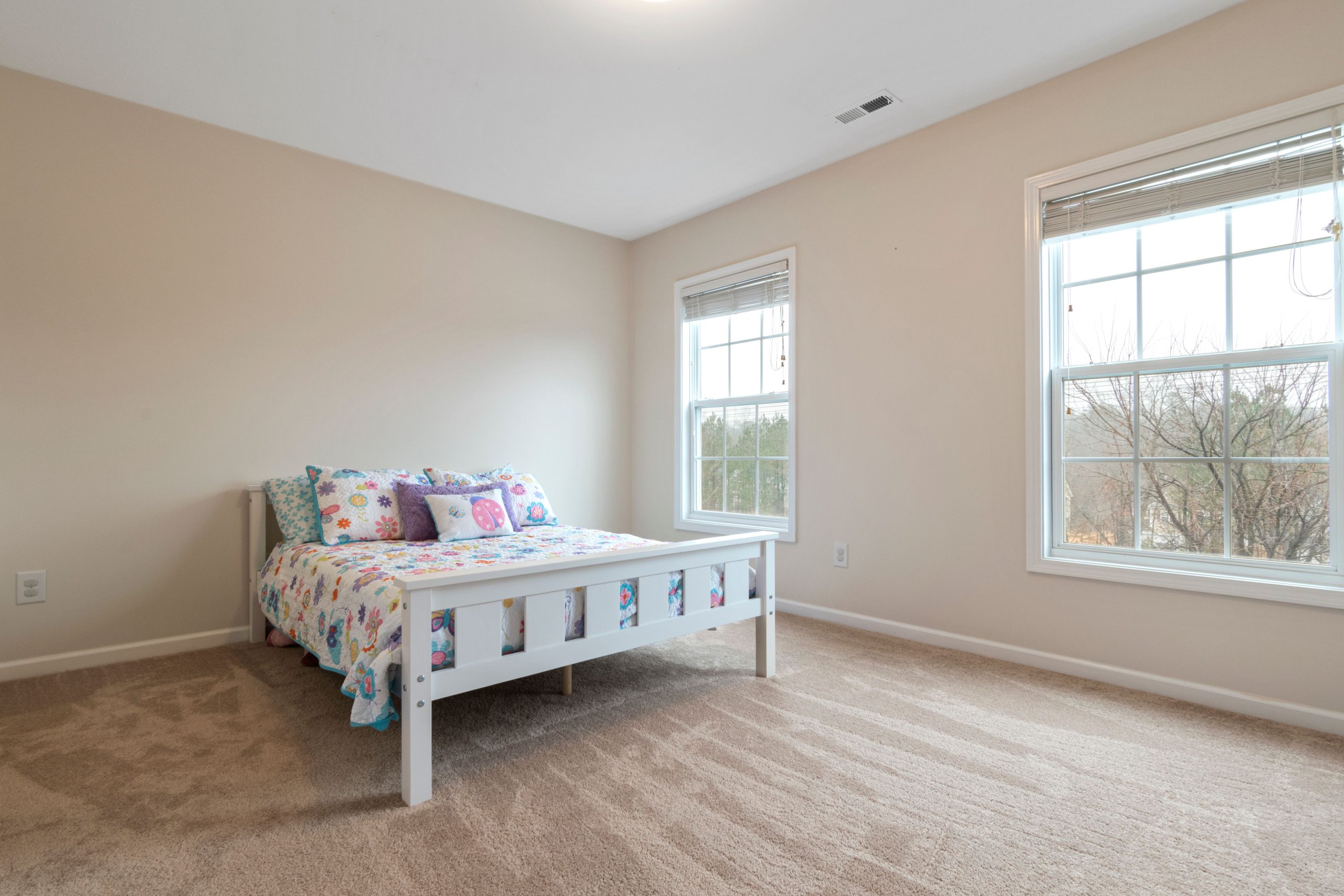 Beige wall-to-wall carpet in a Tennessee bedroom with a white bed frame