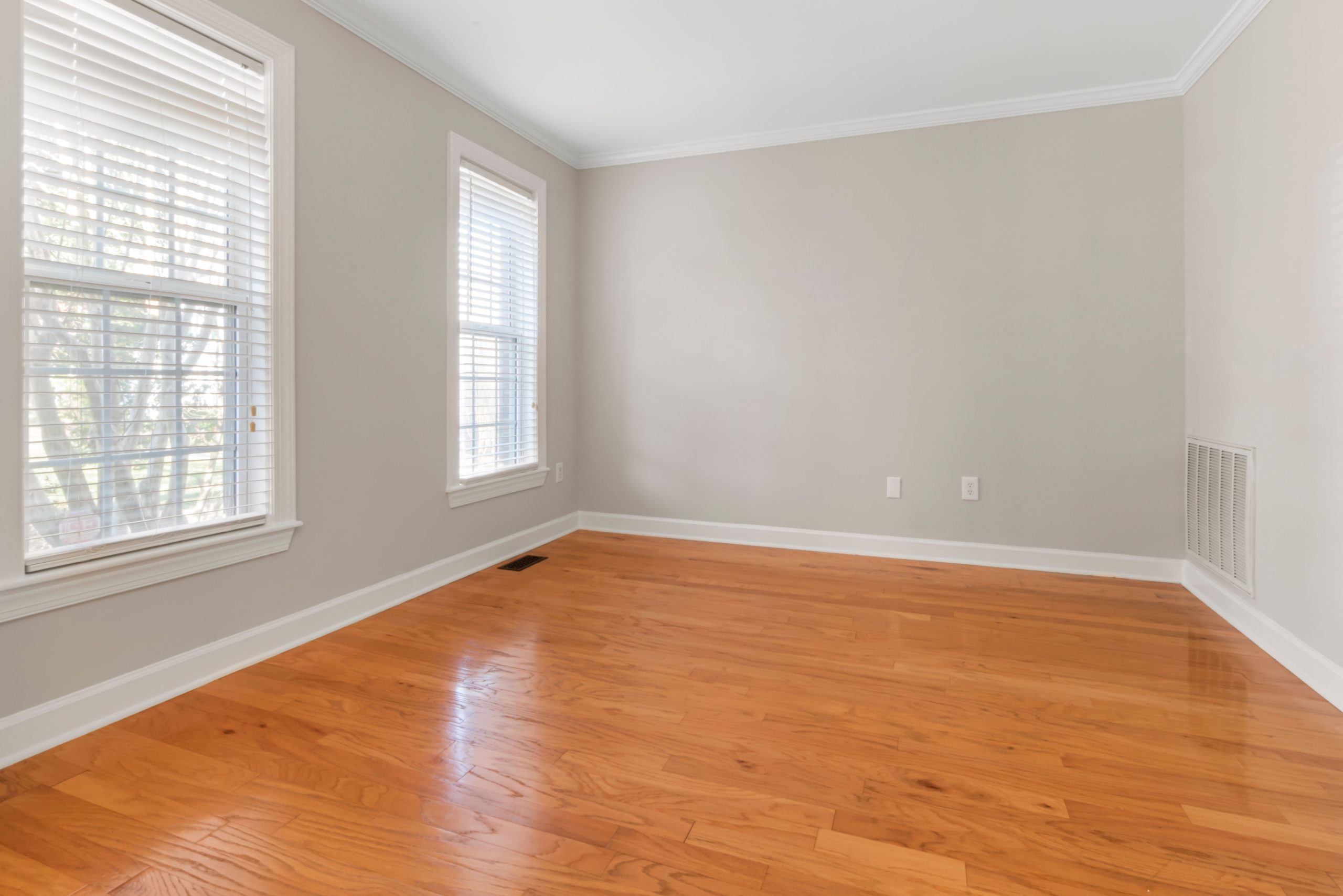 Glossy oak hardwood flooring in an empty Tennessee living room with tall windows