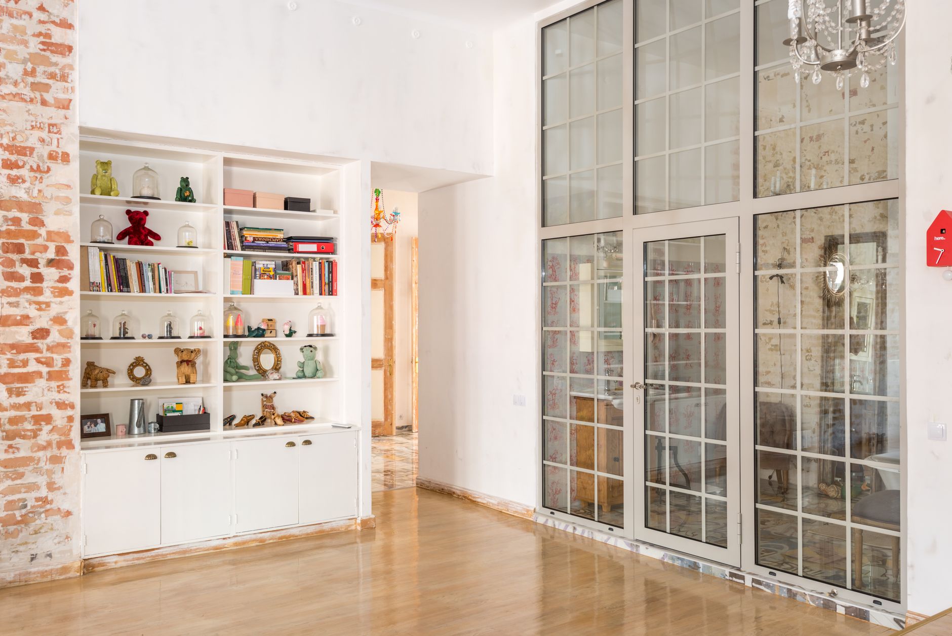Bright interior room with floor-to-ceiling glass doors and decorative shelves