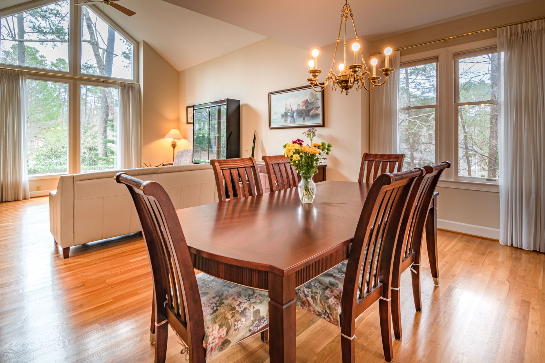 Bright indoor dining area showcasing dark wood furniture, large windows, and modern chandelier