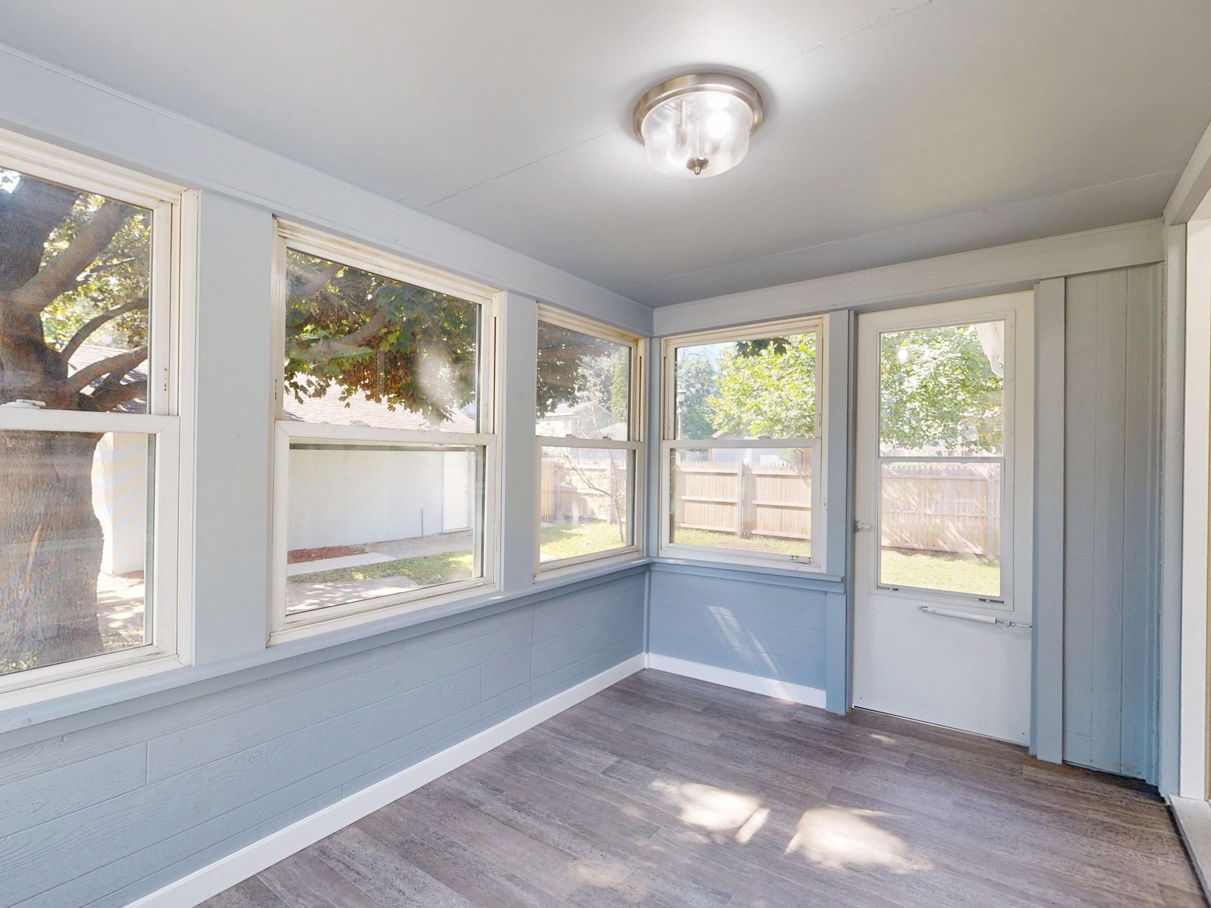 Spacious sunroom with large windows, natural light, and modern flooring